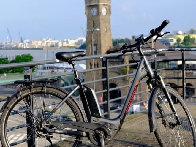 Bicycle on a dock with a clock tower and river in the background.