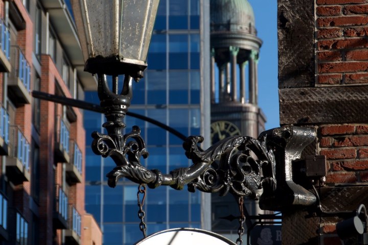 Vintage street lamp and circular sign with buildings in the background.